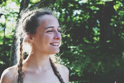 Happy young woman with long braided hair looking away outdoors