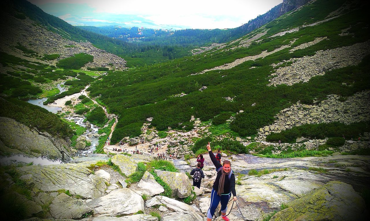 PEOPLE ON GREEN MOUNTAIN AGAINST SKY