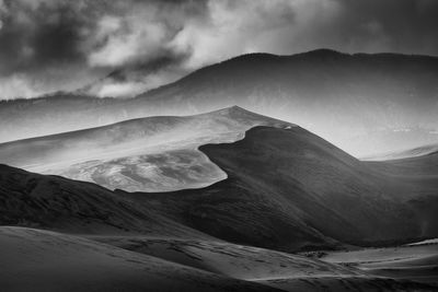 Scenic view of desert against cloudy sky