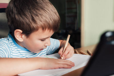 Litle child siting at desk and drawing letters album with colored pencils, lifestyle