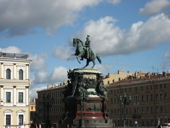 Statue in city against cloudy sky