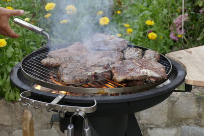 Close-up of man preparing food on barbecue grill in yard