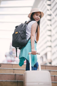 Tourist with luggage on steps in city