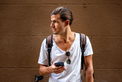 Young latin man with crutches and mobile in the street