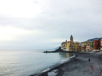 View of city at waterfront against cloudy sky