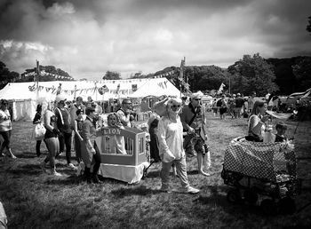 People at cemetery against cloudy sky