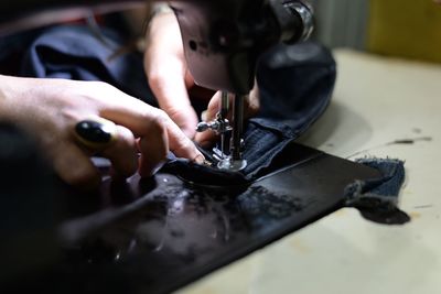 Cropped hand of woman working with sewing machine at home