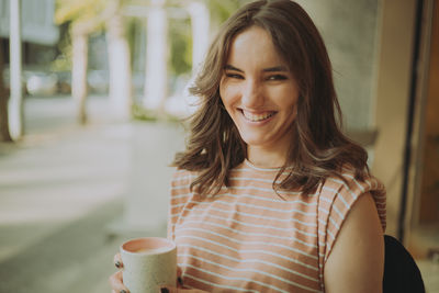 Portrait of young woman using mobile phone in cafe