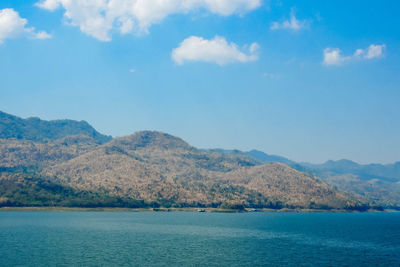 Scenic view of sea and mountains against blue sky