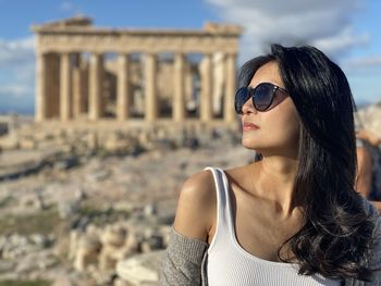 Portrait of young woman wearing sunglasses standing at acropolis