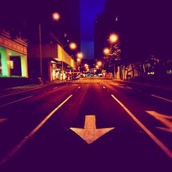 Road passing through illuminated city at night