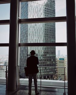 Rear view of woman standing in front of building