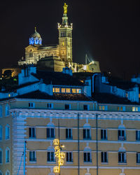 Illuminated basilica of notre dame de la garde overlooking marseille old port at night, france