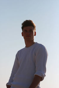 Portrait of young man standing against clear sky