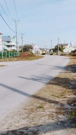 Road by buildings against clear sky