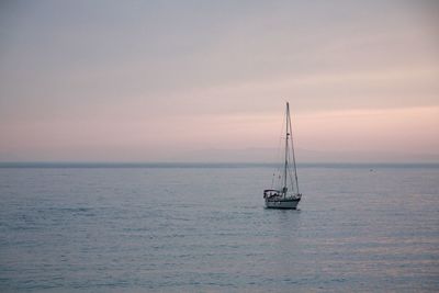 Sailboat sailing on sea against sky during sunset