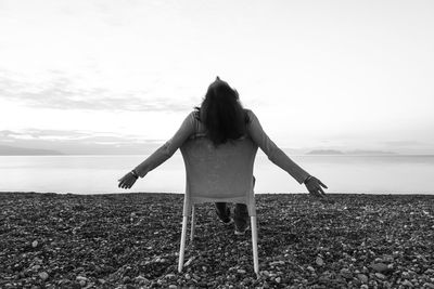 Rear view of woman standing on field against sky