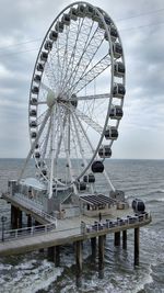 Ferris wheel by sea against sky