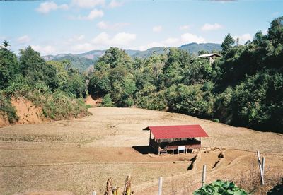 House on field by trees against sky