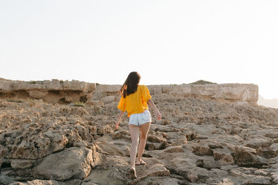 Rear view of woman standing on rock