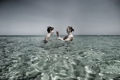 Side view of woman with son enjoying in sea against sky