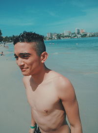 Wet shirtless young man on shore at beach