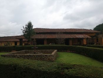 Old building by field against sky