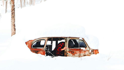 Snow covered car on landscape against sky