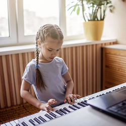 Cute girl playing piano at home