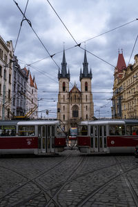 Railroad tracks by buildings in city against sky