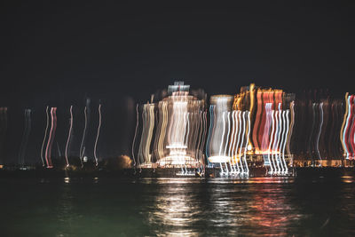 Illuminated glass of water on table against sky at night