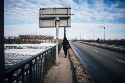 Rear view of man walking on road in winter