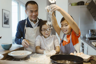 Daughters having fun playing with dough while baking with father at home
