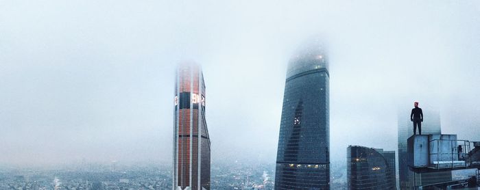 Man standing on building terrace in city during foggy weather