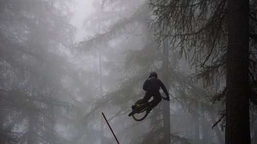 Man with arms raised in forest during winter