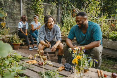 Happy male and female farmers talking while sitting in community garden