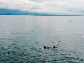 High angle view of people swimming in river against sky