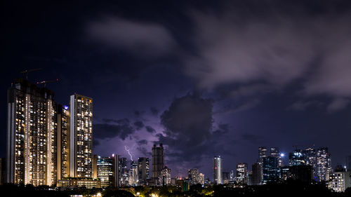 Panoramic view of lightning in illuminated city against sky at night