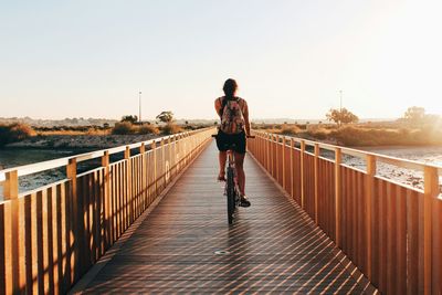 Rear view of man walking on footbridge