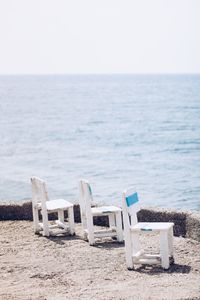 Deck chairs on beach against clear sky