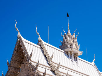 Low angle view of statue against building against clear blue sky