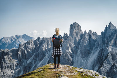 Rear view of man standing on mountain against sky