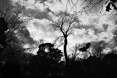 Low angle view of trees against cloudy sky