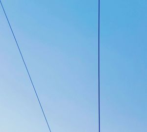 Low angle view of electricity pylon against clear blue sky