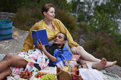 Female couple having picnic and reading book