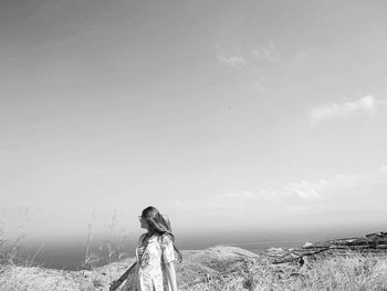 Rear view of woman standing on field against sky