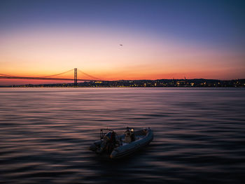 Bridge over river in city at sunset