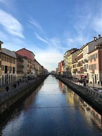 Canal in city against sky