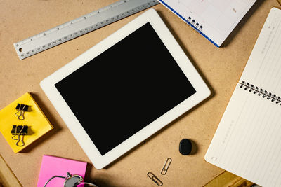 Directly above shot of digital tablet with office supply on desk