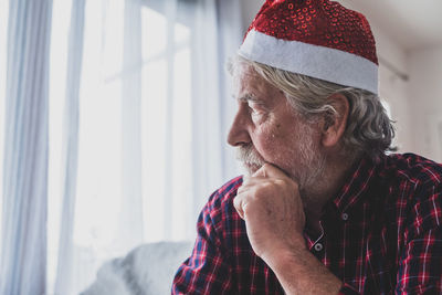 Side view of young man looking through window at home